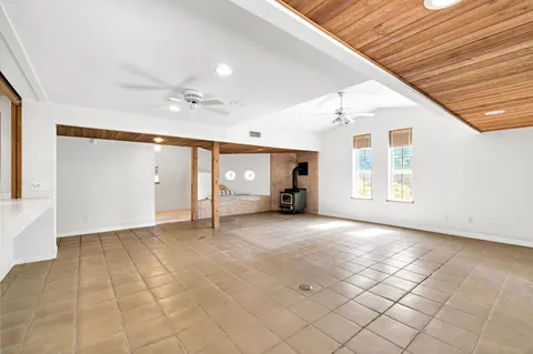 a view of an empty room with a fireplace and a ceiling fan
