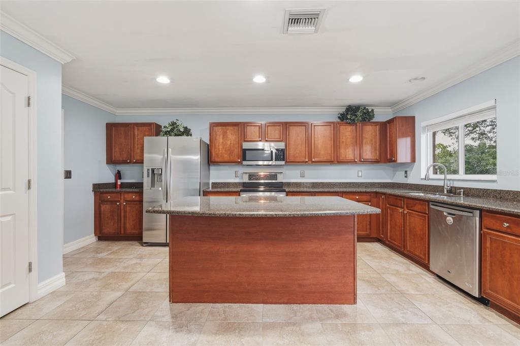 25134 Palisade Road Punta Gorda, FL 33983 - Photo 17 of 58 a large kitchen with stainless steel appliances wooden cabinets a stove a sink a microwave and a refrigerator