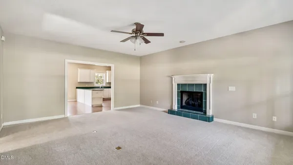 a view of a livingroom with a fireplace a ceiling fan and windows