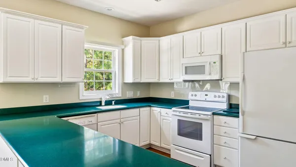 a kitchen with granite countertop white cabinets and white appliances