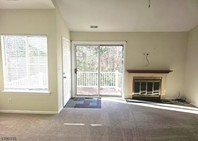 a view of an empty room with a fireplace and a window