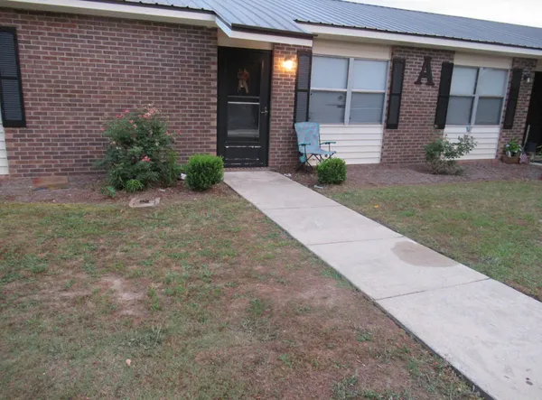 a front view of a house with a yard and glass top table and chair