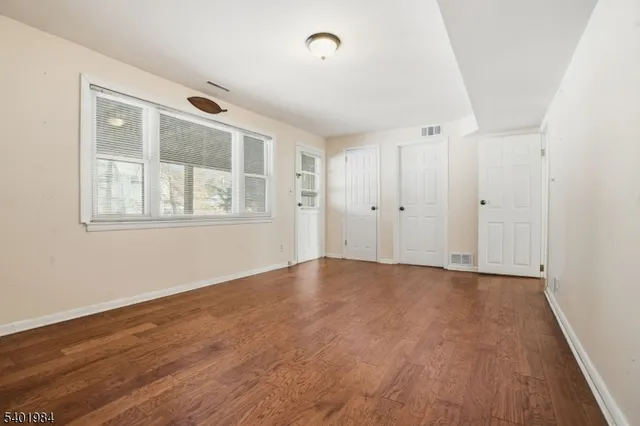 a view of an empty room with wooden floor and windows