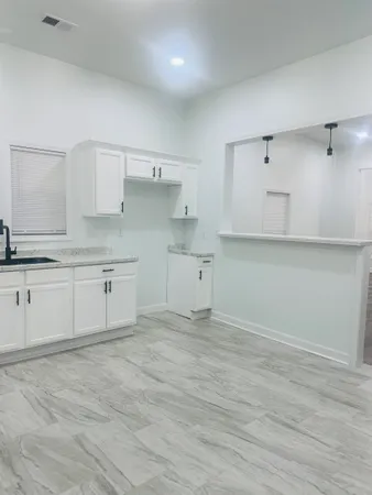 a view of kitchen and empty room with wooden floor