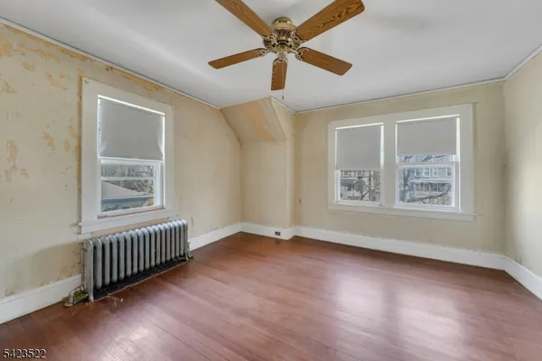 a view of an empty room with a window and wooden floor