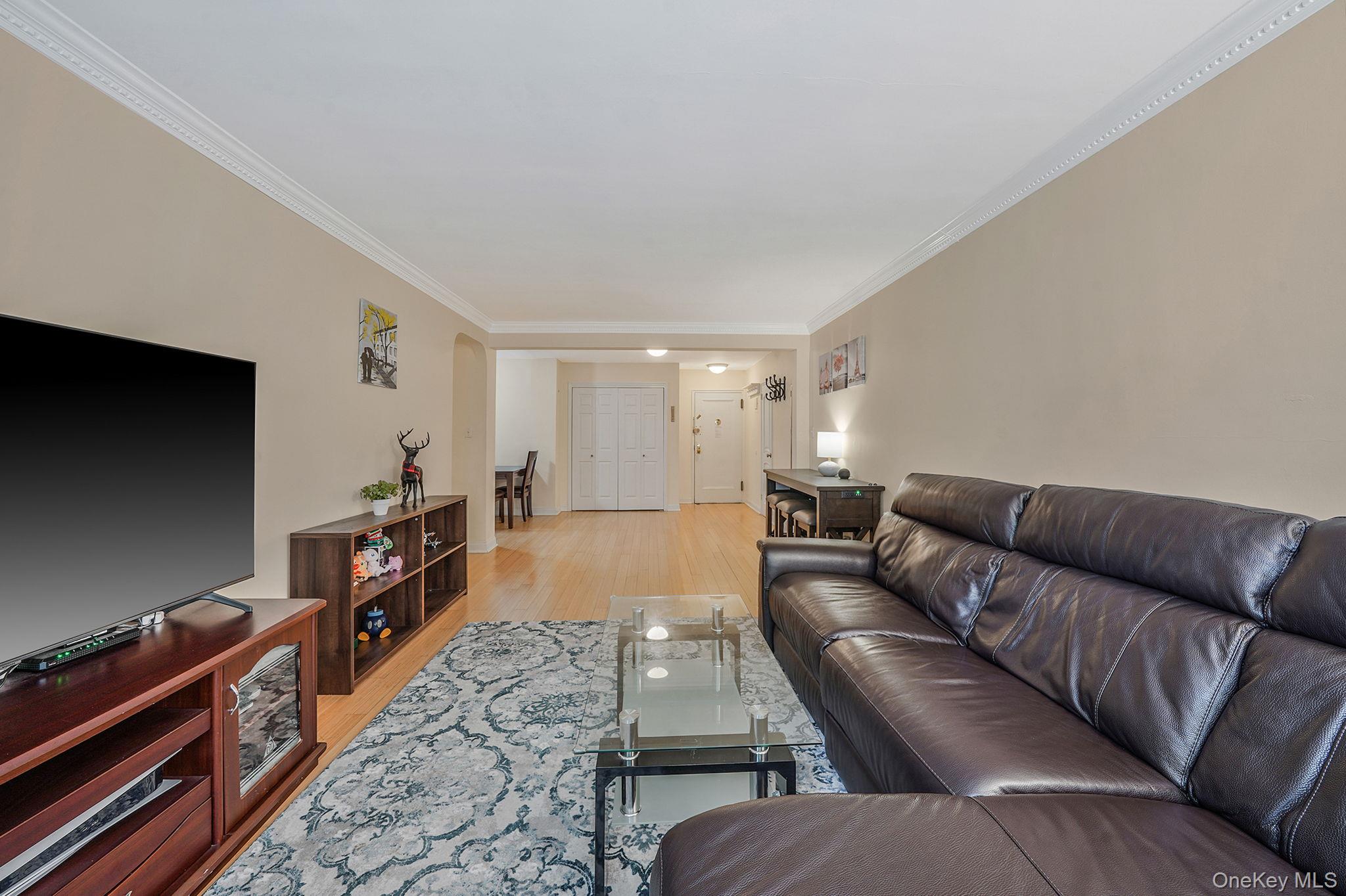 103-26 68th Avenue, Unit 2E Queens, NY 11375 - Photo 9 of 22 Living area with crown molding and light wood finished floors