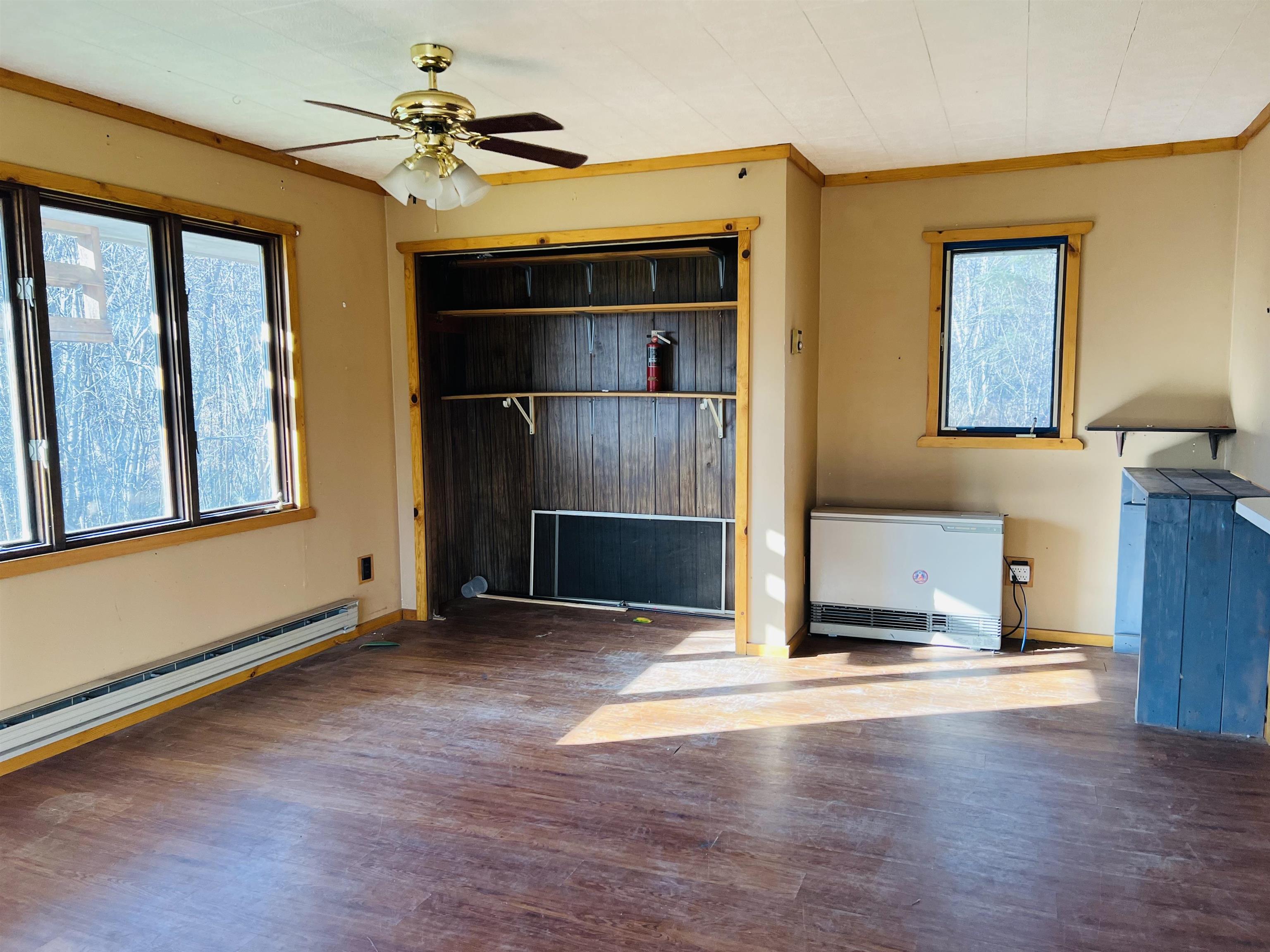 118 Rollins Ridge Tofte, MN 55615 - Photo 8 of 18 Unfurnished living room with crown molding, wood finished floors, a ceiling fan, and heating unit