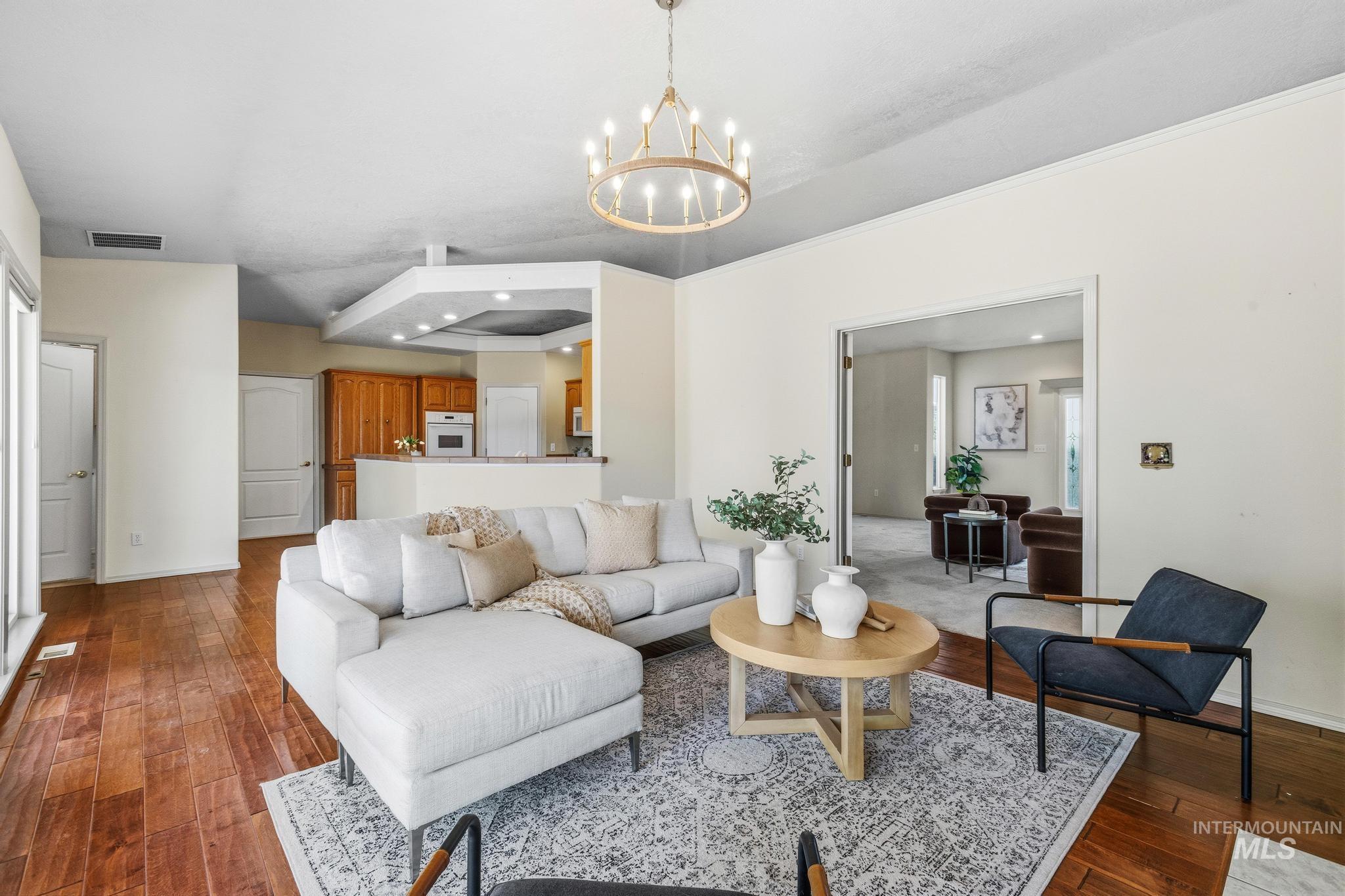 15181 Drury Way Caldwell, ID 83607 - Photo 15 of 49 Spacious living area featuring wood-finish flooring, a contemporary chandelier, and an open entryway to an additional room