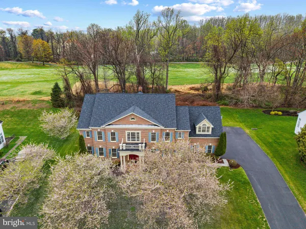 a view of a big house with a big yard and large trees