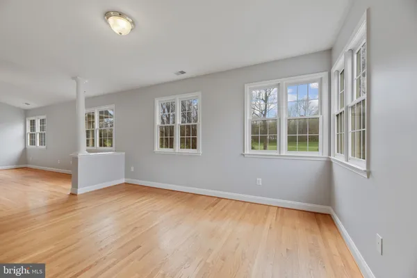 an empty room with wooden floor and windows