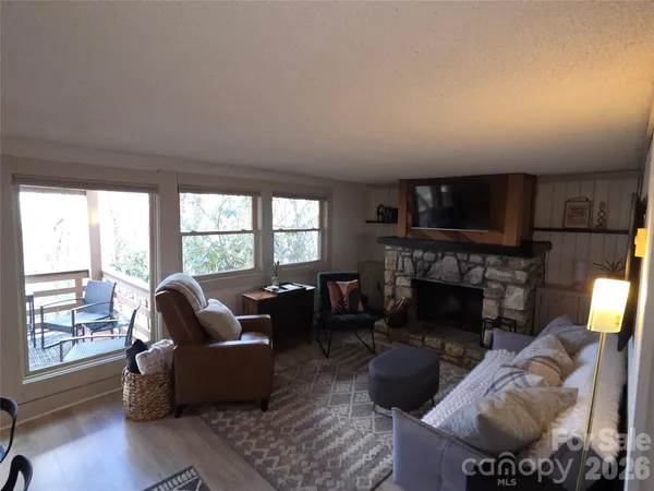 a living room with furniture a fireplace a flat screen tv and a large window