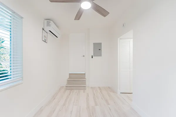 a view of an empty room with wooden floor and a window