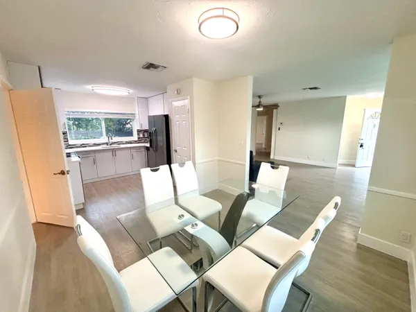 a living room with stainless steel appliances furniture a rug and a kitchen view