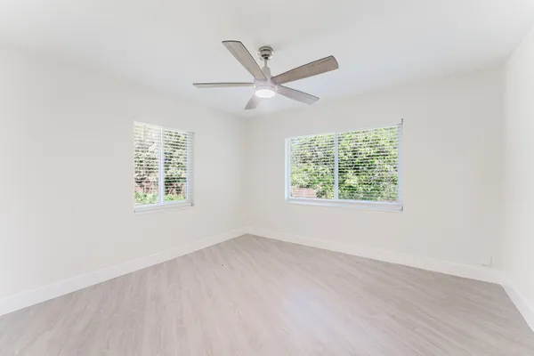 an empty room with a window and a ceiling fan