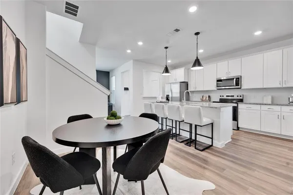 a kitchen with stainless steel appliances kitchen island granite countertop a dining table chairs and a refrigerator