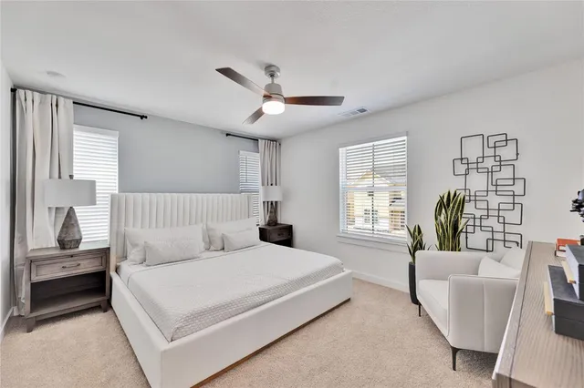 a bedroom with a large bed couch and windows