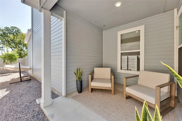 a balcony with couple of chairs and a potted plant