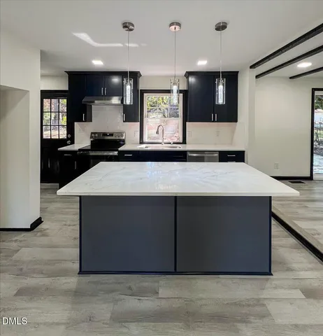 a kitchen with stainless steel appliances kitchen island granite countertop a stove and a refrigerator