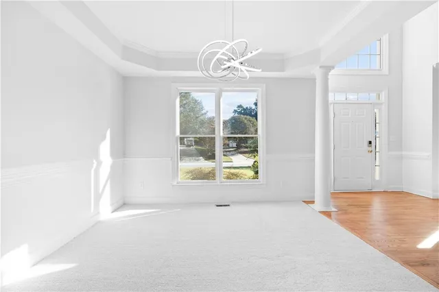 a view of an empty room with wooden floor and windows