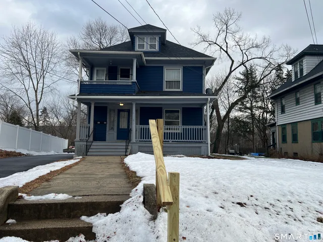 a front view of a house with a yard covered with snow