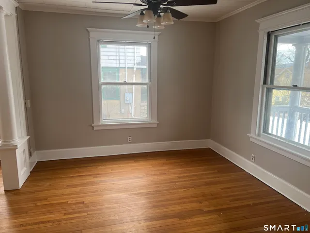 a view of an empty room with wooden floor and a window