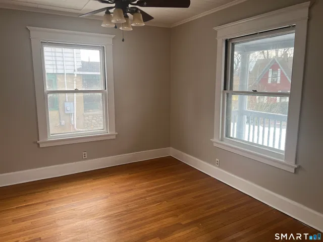 a view of an empty room with wooden floor and a window