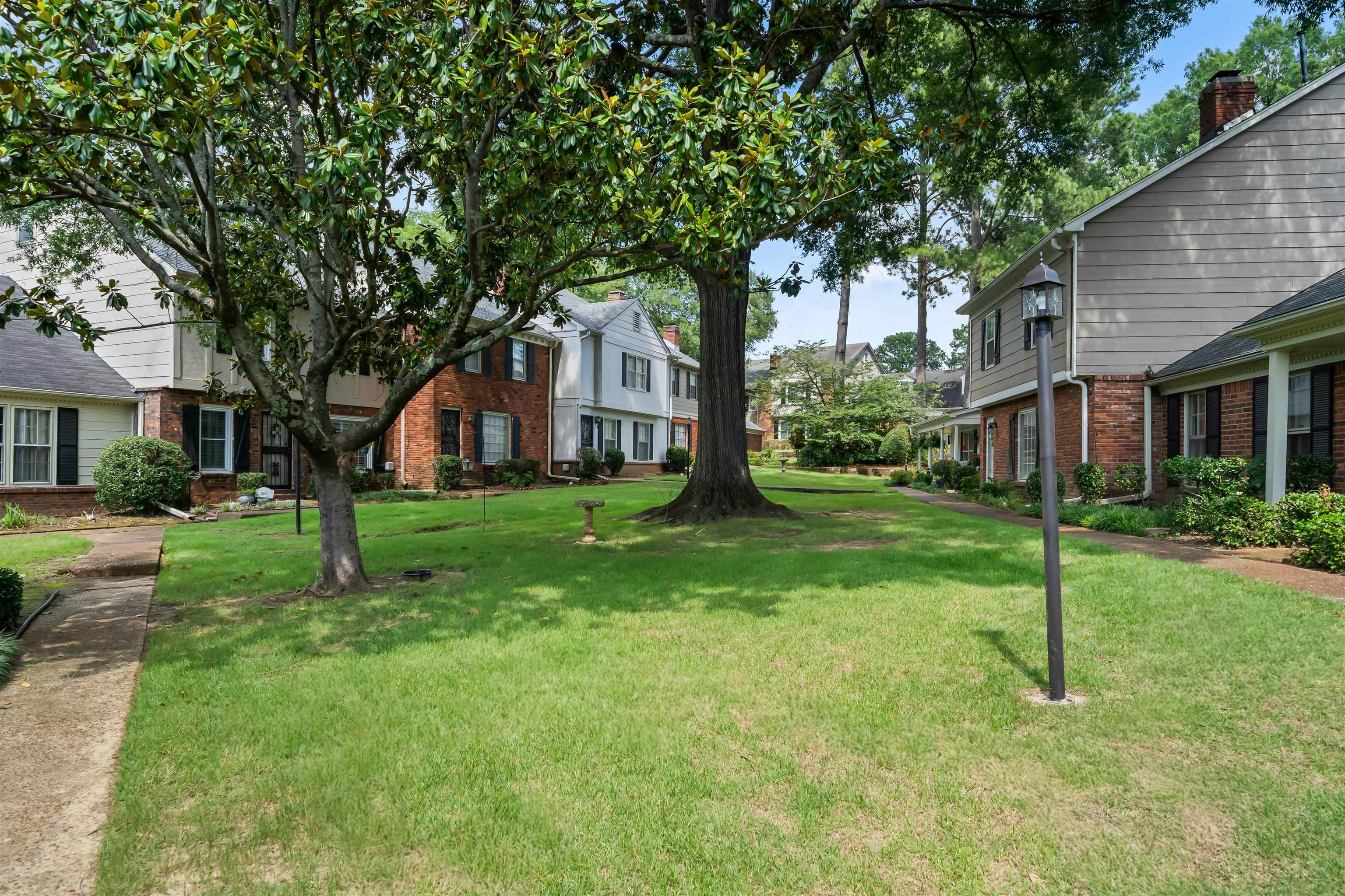 6943 Fords Station Road, Unit 64 Germantown, TN 38138 - Photo 19 of 30 Expansive green space featuring mature trees, a paved walkway, a traditional street lamp, and brick and siding residential exteriors