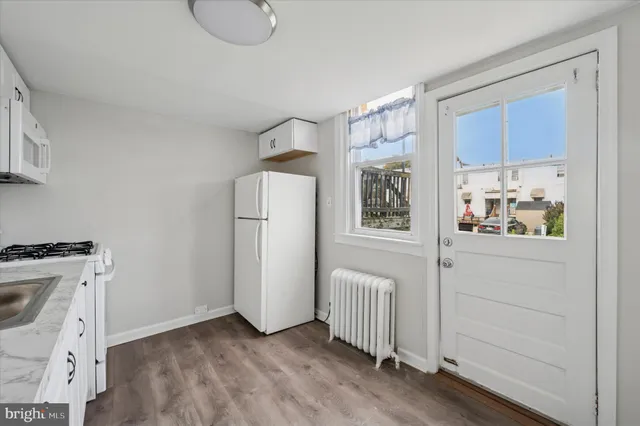 a view of a kitchen with refrigerator and wooden floor