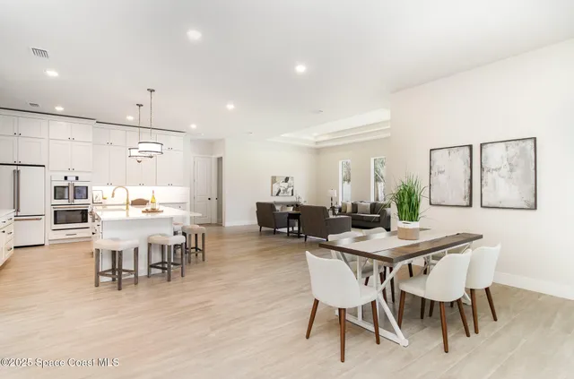 a kitchen with stainless steel appliances refrigerator dining table and chairs