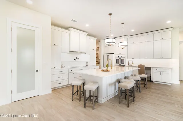 a kitchen with center island white cabinets and stainless steel appliances