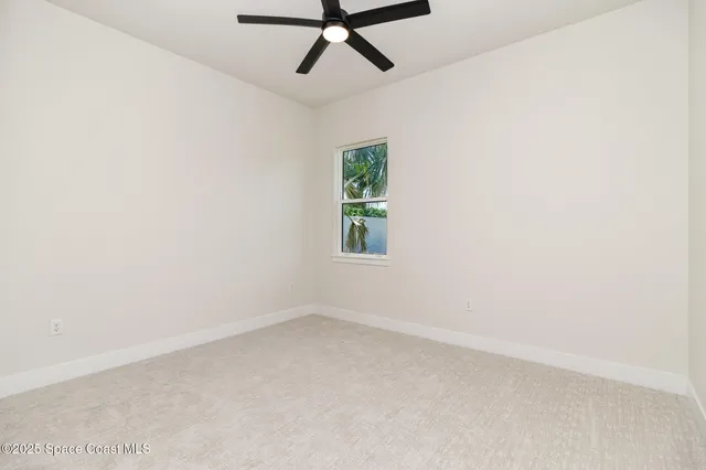 an empty room with a ceiling fan and carpet