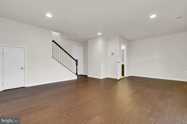 a view of an empty room with wooden floor and staircase