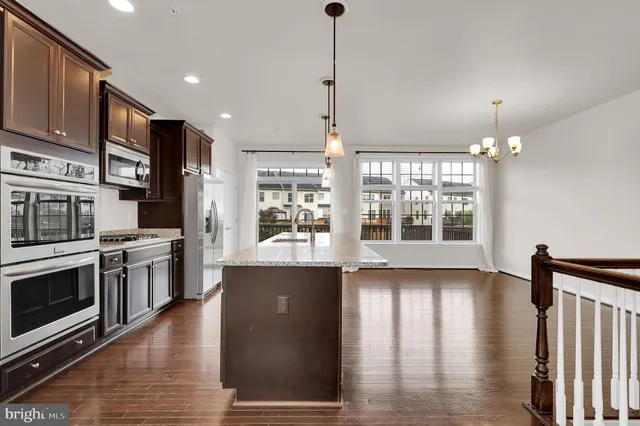 a kitchen with stainless steel appliances granite countertop a stove and a wooden floors
