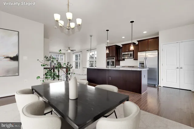 a open dining room with furniture a chandelier and wooden floor