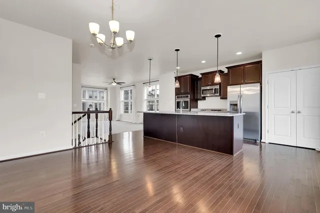 a large kitchen with white cabinets stainless steel appliances and wooden floor
