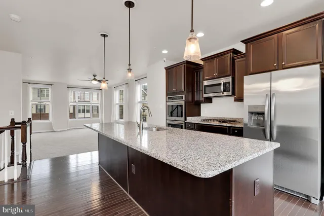 a kitchen with stainless steel appliances kitchen island granite countertop a kitchen island a microwave a stove and a refrigerator