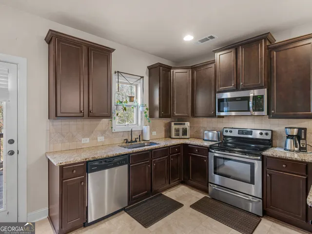 a kitchen with stainless steel appliances granite countertop a sink stove and microwave