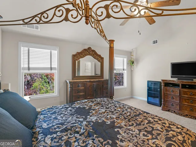 a bedroom with a bed and a flat tv screen on the dresser