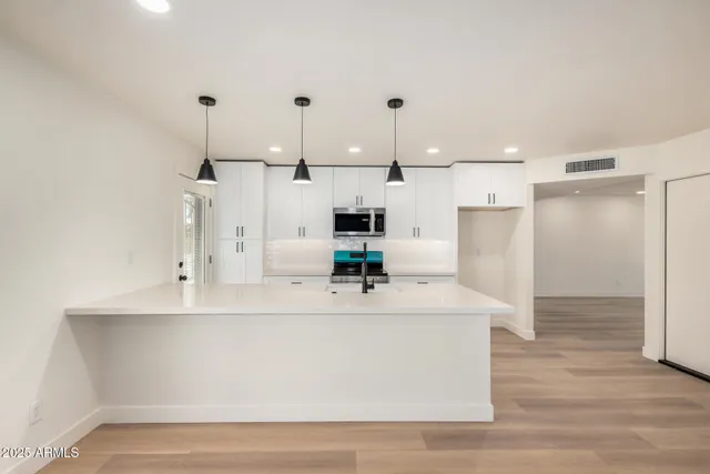 a large white kitchen with stainless steel appliances