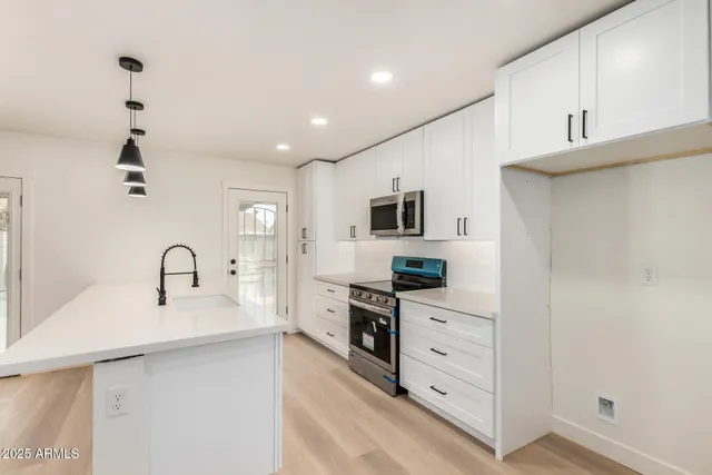 a kitchen with white cabinets and wooden floor