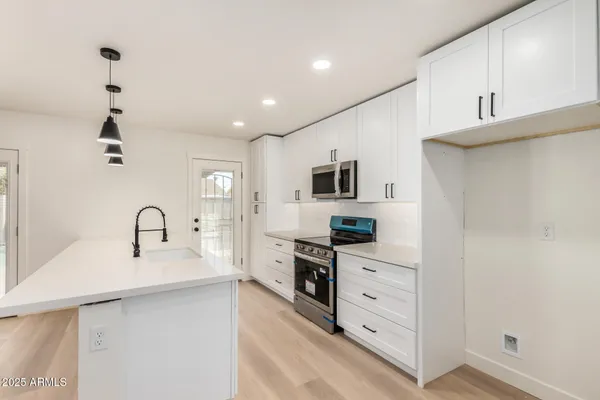 a kitchen with white cabinets and wooden floor