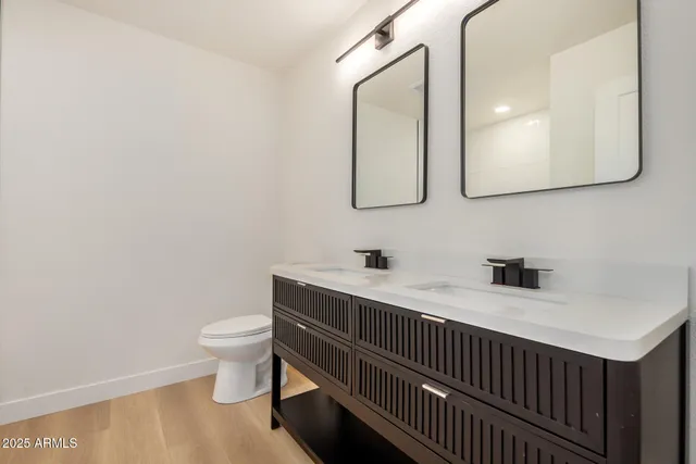 a bathroom with a toilet sink double vanity and mirror
