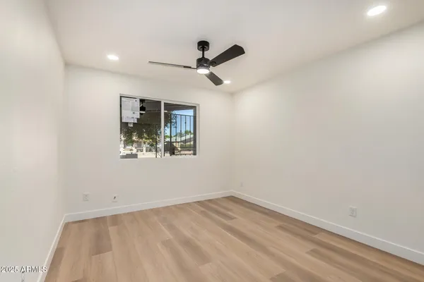 an empty room with a ceiling fan and window