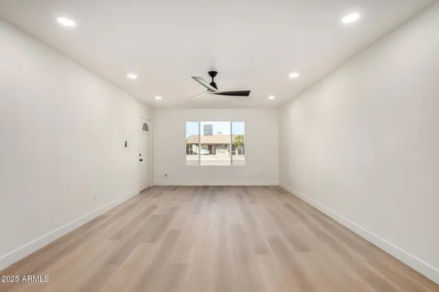 an empty room with a window and a ceiling fan