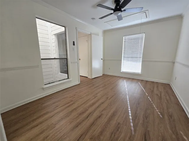 an empty room with wooden floor a ceiling fan and windows