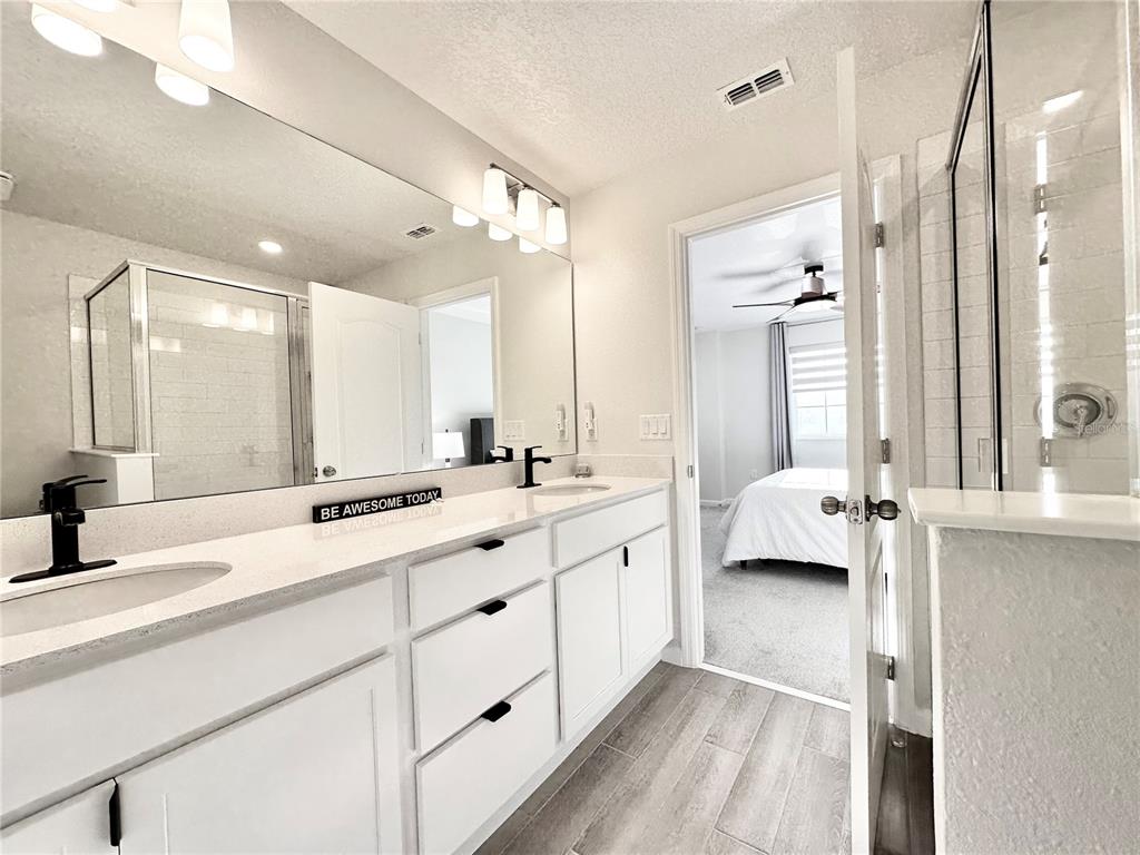 2767 North Narcoossee Road, Unit 2767 St. Cloud, FL 34771 - Photo 11 of 19 a large bathroom with a double vanity sink and mirror with shower