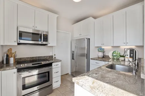 a kitchen with granite countertop a stove a microwave a sink a refrigerator and cabinetry