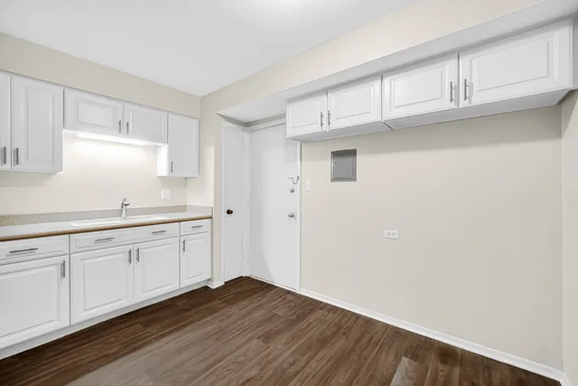 a kitchen with granite countertop white cabinets and wooden floor