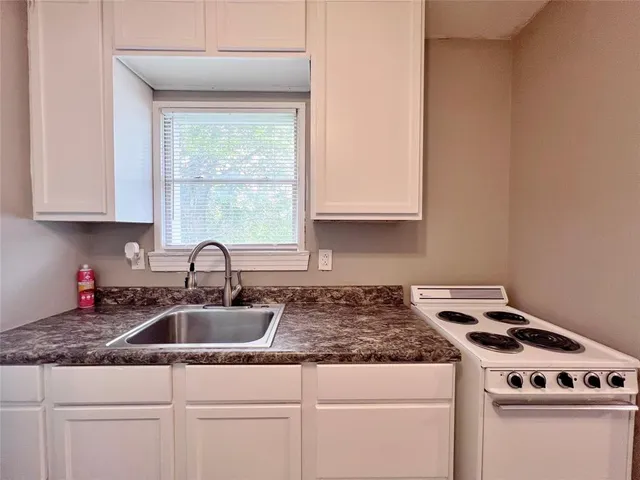 a kitchen with granite countertop a sink a stove and cabinets
