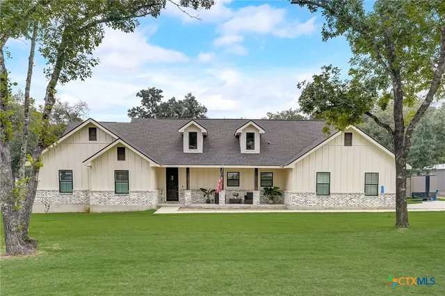 a view of house with a big yard and large trees